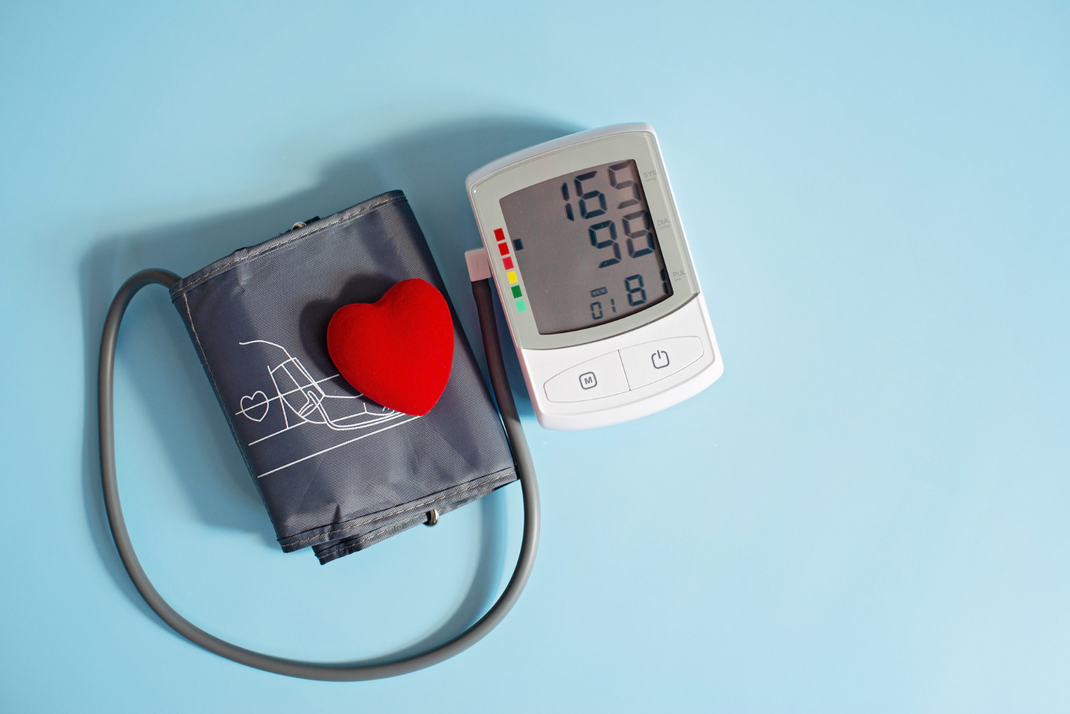 223 A blood pressure monitor with a cuff and a small red heart on a blue background.